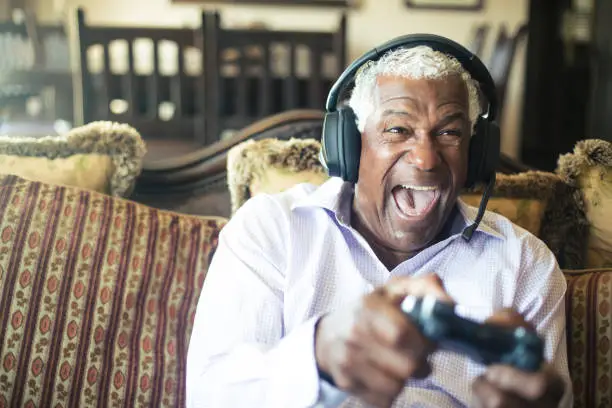 Photo of Senior Black Man Playing Video Games with Headphones