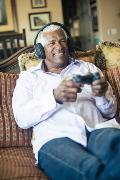 istock Senior Black Man Playing Video Games with Headphones 935695968