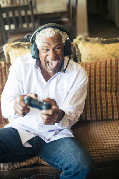 istock Senior Black Man Playing Video Games with Headphones 935696106