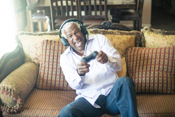 istock Senior Black Man Playing Video Games with Headphones 935696820