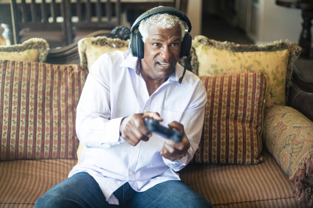 istock Senior Black Man Playing Video Games with Headphones 935697772