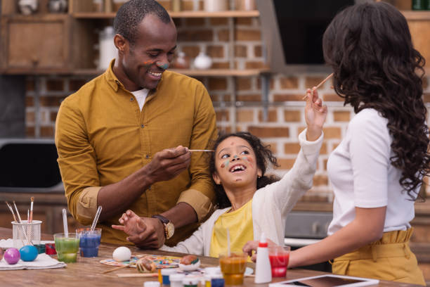 istock happy african american parents and daughter having fun while painting easter eggs 935698730