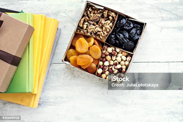 Foto de Uma Caixa De Nozes E Frutas Secas E Uma Pilha De Livros e mais fotos de stock de Lanche