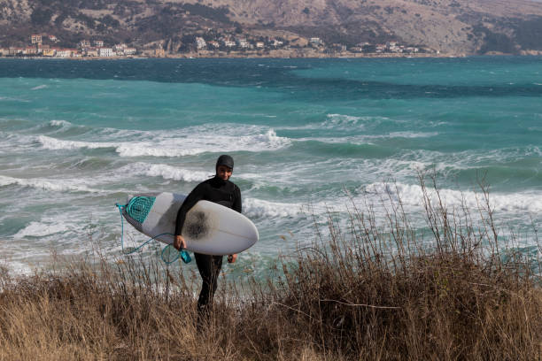 istock Surfer holding a surfboard and walking toward the sea 935701942