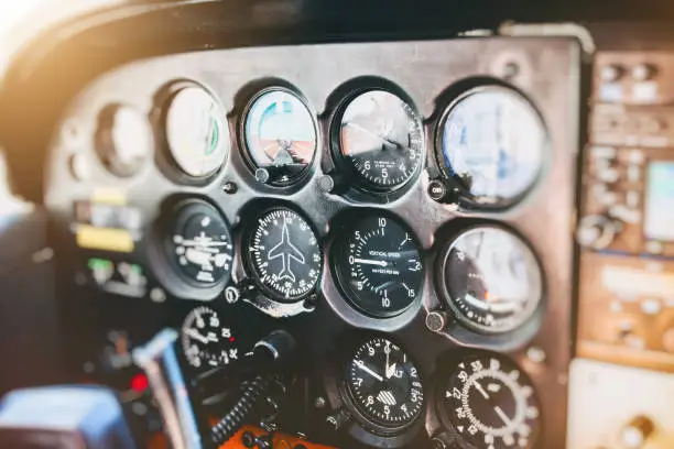 Vibrant color photography horizontal composition of close-up on several common flight instruments in old small propeller airplane cockpit interior without people in the frame, and selective focus on control panel dashboard.