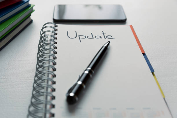 istock Update - handwritten text in a notebook on a desk. Project update checklist. Notebook, pen and books 935705412