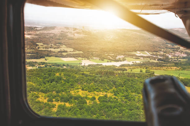 istock Looking through small flying plane window at sunset in summer in countryside POV view 935705766