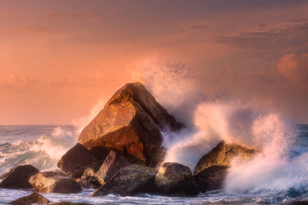 Tropical beach with rocks and big crashing waves Tropical beach with rocks and big crashing waves at sunset Mirissa, Sri Lanka breaking wave stock pictures, royalty-free photos & images