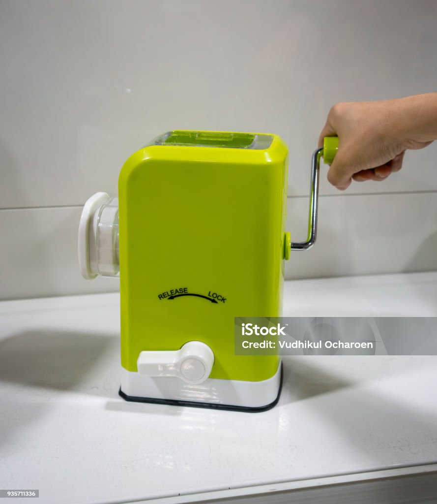 Hand Holding Mini Kitchen Tools For Manual Meat Grinder With Plastic  Container And Green Body Against White Wall Stock Photo - Download Image  Now - iStock