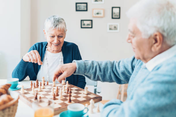 Senior couple playing chess at home Happy senior couple playing chess senior chess stock pictures, royalty-free photos & images