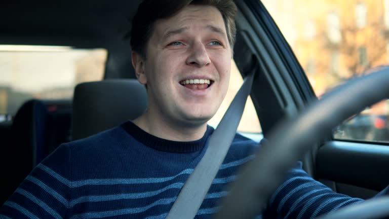 A young man is driving a car and singing