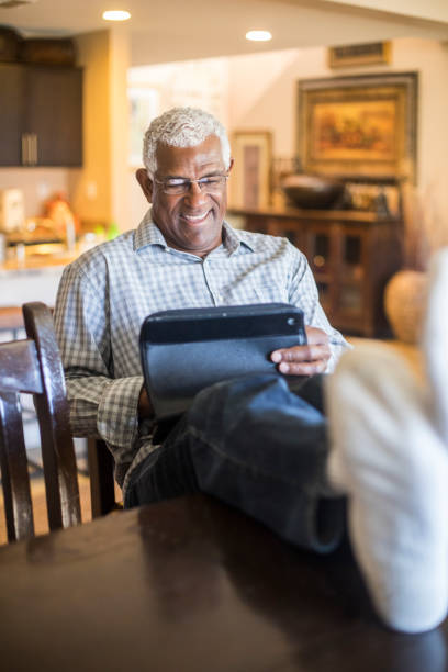 istock Relaxed Senior Black Man Working on Tablet in Kitchen at Home 935722462