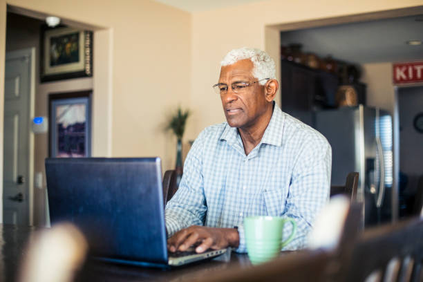 Senior Black Man Working on Laptop Computer at Home A senior black man works from his computer at home white hair photos stock pictures, royalty-free photos & images