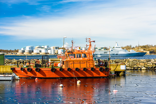 Karlshamn, Sweden - March 19, 2018: Documentary of everyday life and environment. Swedish pilot vessel 218 SE in harbor. Visby class navy corvette vessel K35 Karlstad passing behind.