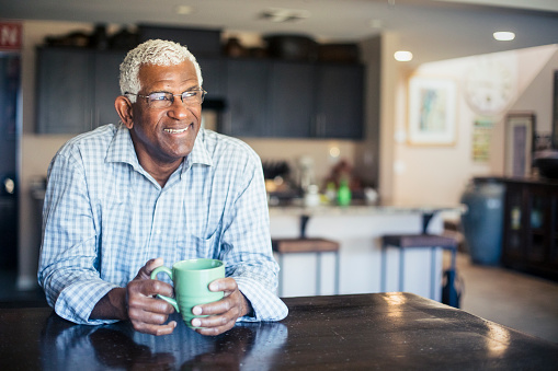 A senior black man enjoys a cup of coffee at home