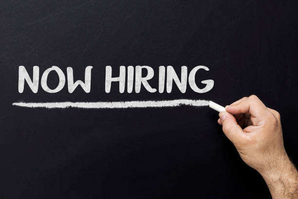 istock Hand with chalk writing Now hiring on black chalkboard 935729684