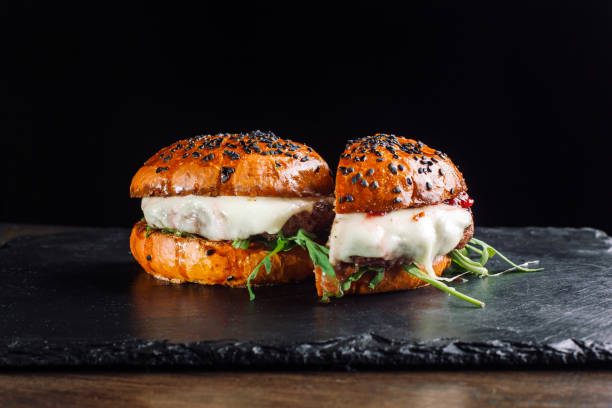 istock Hamburger on a black slate board. It is cut in half 935732238