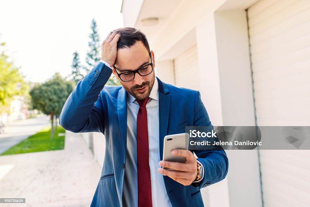 Checking phone Handsome suited businessman checking his smart phone Reminder Stock Photo