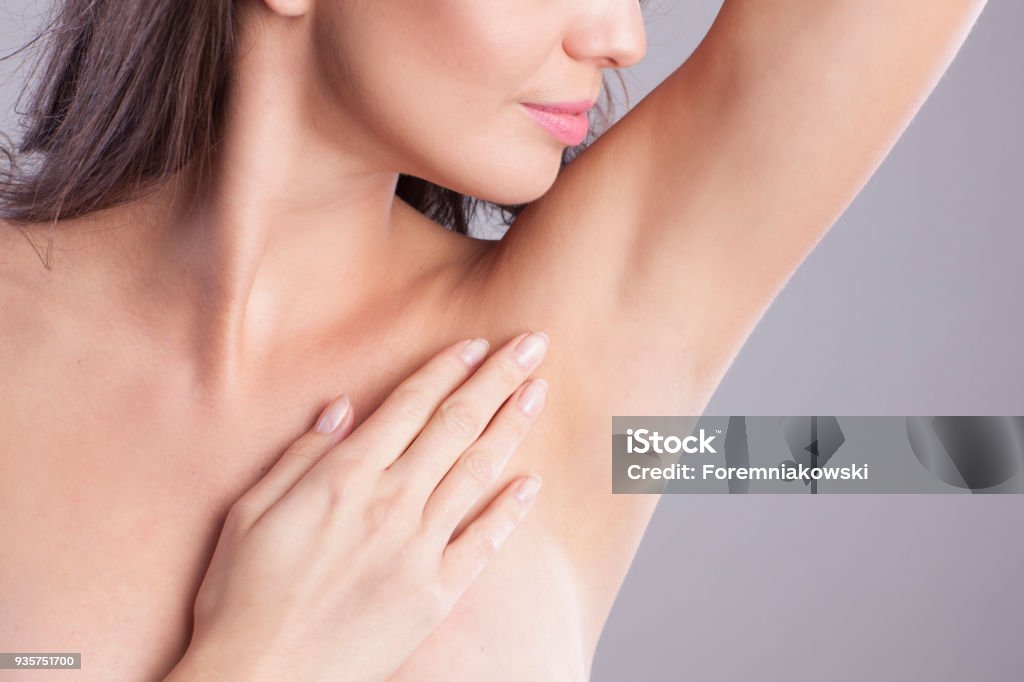 Close up of female armpit. Adult model touching her smooth axilla. Hair Removal Stock Photo