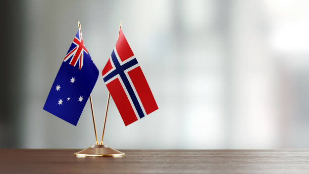 istock Australian And Norwegian Flag Pair On A Desk Over Defocused Background 935761046