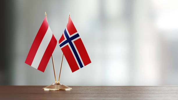 istock Austrian And Norwegian Flag Pair On A Desk Over Defocused Background 935767988