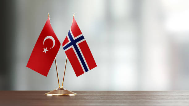 istock Turkish And Norwegian Flag Pair On A Desk Over Defocused Background 935768090