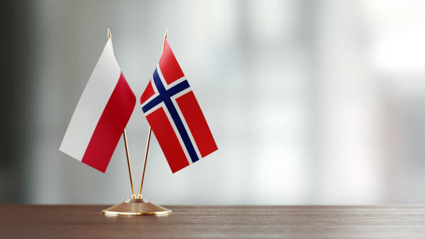 istock Polish And Norwegian Flag Pair On A Desk Over Defocused Background 935768624