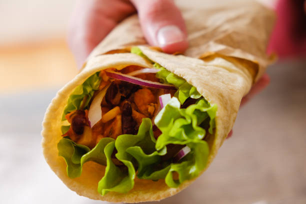 istock Mexican burrito in hand with chicken, pepper and beans 935771056