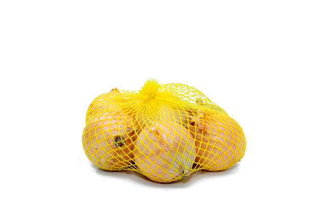 des oignons dans un filet en plastique jaune - onion bag netting vegetable photos et images de collection