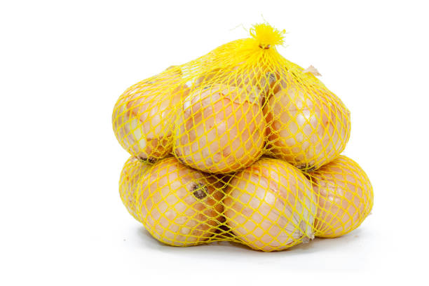 des oignons dans un filet en plastique jaune - onion bag netting vegetable photos et images de collection