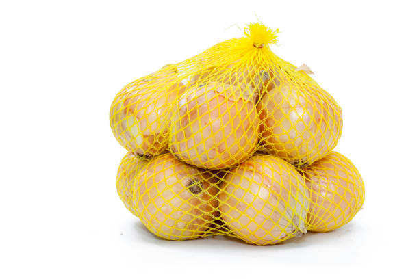 свежий лук в желтой пластиковой сетке - onion red isolated yellow стоковые фото и изображения
