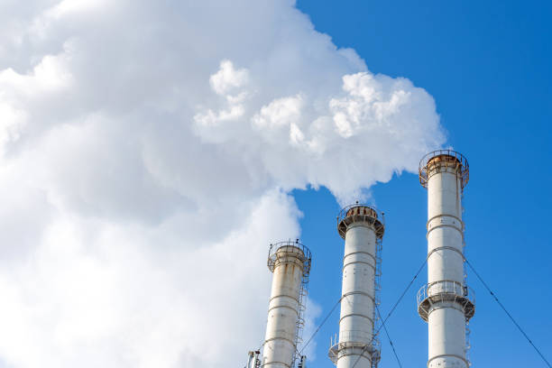 Smoking pipes making clouds against blue sky background. Dioxide air contamination. Environmental pollution.