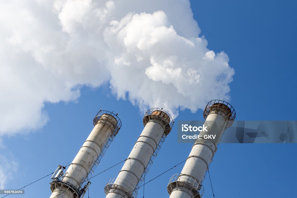 Smoking pipes making clouds against blue sky background. Dioxide air contamination. Environmental pollution Smoking pipes making clouds against blue sky background. Dioxide air contamination. Environmental pollution. Fumes Stock Photo