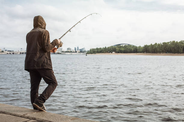 istock Young man fishing with a spinning on the river 935782152