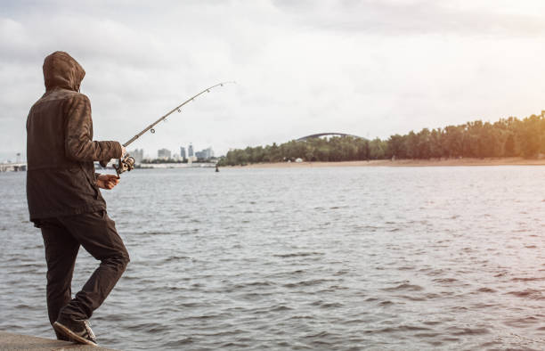 istock Young man fishing with a spinning on the river 935782184
