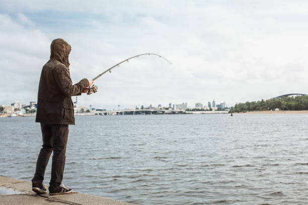 istock Young man fishing with a spinning on the river 935782224