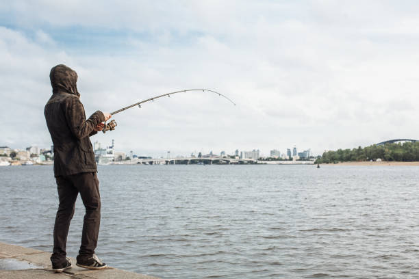 Young man fishing with a spinning on the river stock photo