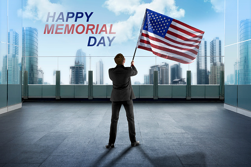 Businessman waving American flag for happy memorial day with blue sky background