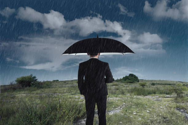 istock Businessman with an umbrella standing under the rain 935784962