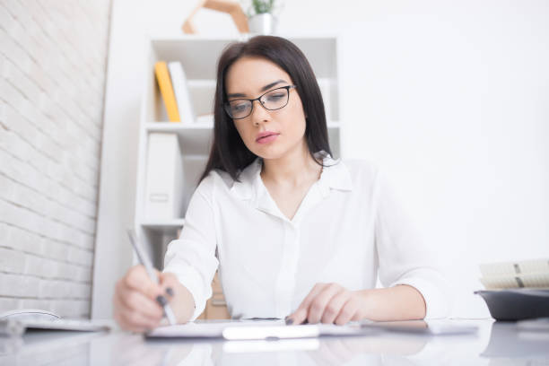 istock Busy young woman making notes at desk 935794954