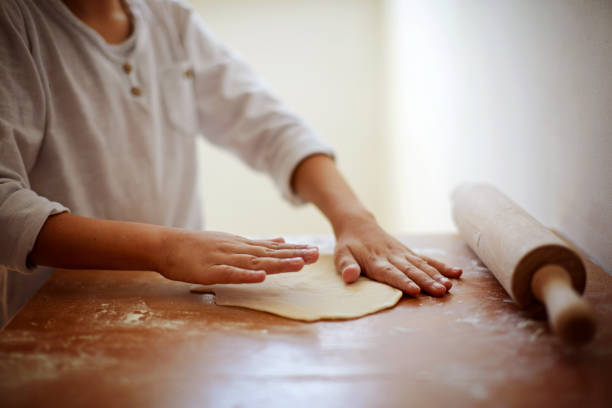istock Hands teenage boy with a rolling pin roll the dough for pizza 935797592