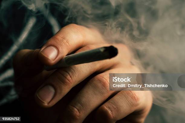 Cannabis Weed A Joint In His Hands A Man Smokes Smoke On A Black Background Concepts Of Medical Marijuana Use And Legalization Of The Cannabis Stock Photo - Download Image Now