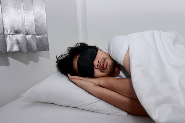 istock Young Asian man with mask comfortable sleeping on the bed in home. 935837092