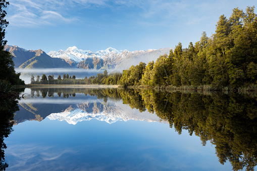 Lake Matheson is situated on the West Coast of New Zealand and is know for its reflections of Mount Tasman and Mount Cook (New Zealand's hightest mountain) in it's still waters. Native rain forest surrounds the lake and is also reflected in the waters. Early morning mist hangs just above the trees.\nLake Matheson is a very poplular location with tourists.