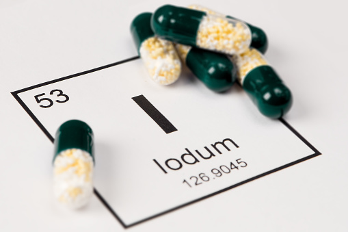 Pills with mineral I (iodium, iodine) on a white background with an inscription from the chemical table