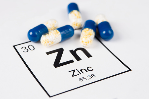 Pills with mineral Zink (Zincum) on a white background with an inscription from the chemical table