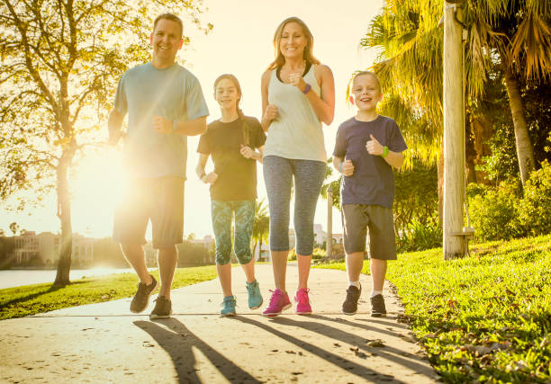 familiares hacer ejercicio y correr juntos en el parque - family sport exercising jogging fotografías e imágenes de stock