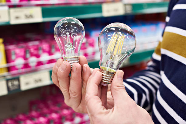 istock LED and incandescent lamp in hands on store 935906638
