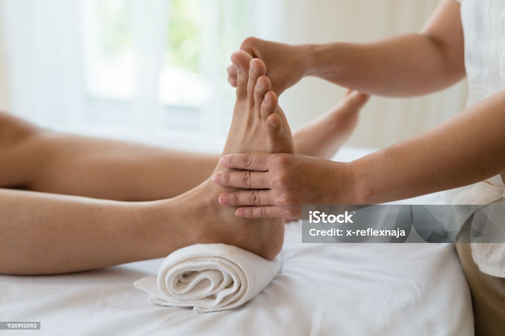 Asian girl relaxing having feet massage in a spa salon, close up view Reflexology Stock Photo