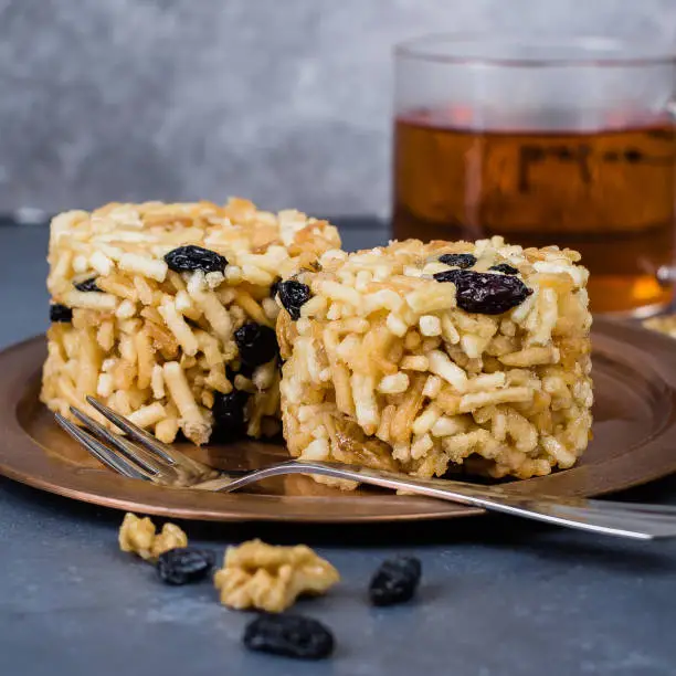 Photo of Eastern or Asian sweets (chak-chak) with honey, raisins and walnut on stone concrete table background. Copy Space